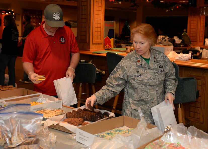 Maj. Olga Brandt, 5th Contracting Squadron commander, and Shaun Beal, Officers’ Spouses’ Club president, prepare bags of holiday cookies during the 2015 Airmen Cookie Drive at Minot Air Force Base, N.D., Dec. 11, 2015. The holiday cookie drive for Minot Airmen is a yearly event engineered to reach out to young Airmen who live in the dorms and for those working during the holidays. (U.S. Air Force photo/Airman 1st Class Matt Rauschnot)