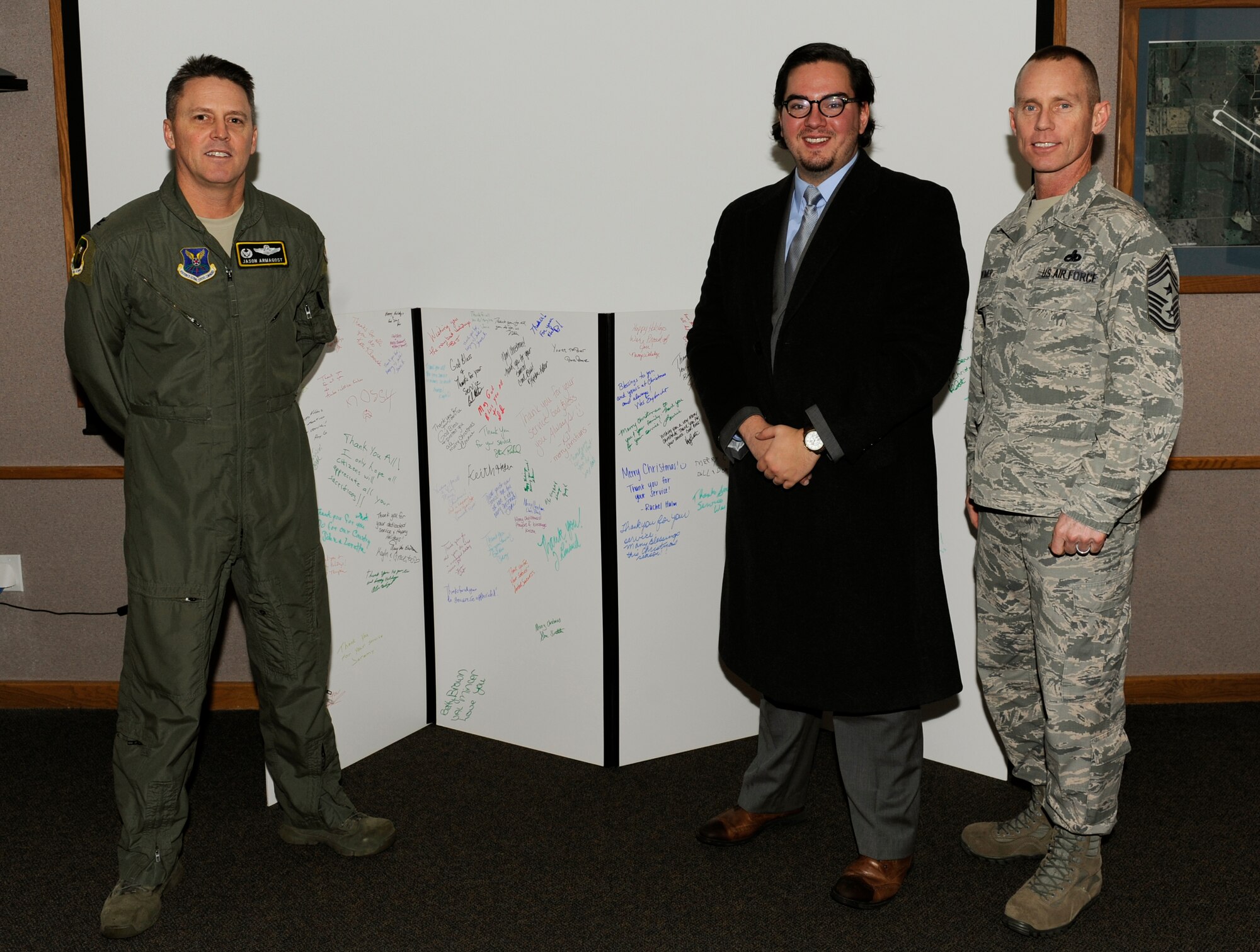 Jarrod Anderson, executive director of The American Red Cross - Western North Dakota, presents a Christmas card to 5th Bomb Wing leadership at Minot Air Force Base, N.D., Dec. 16, 2015. Every year the Red Cross presents MAFB with a giant Christmas card signed by businesses and community members throughout the state to show their appreciation and support. (U.S. Air Force photo/Senior Airman Sahara L. Fales)