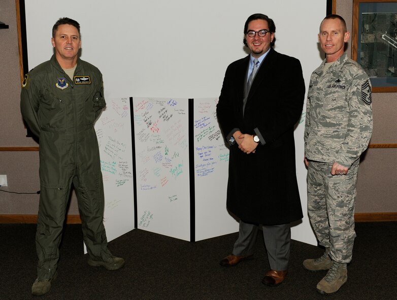 Jarrod Anderson, executive director of The American Red Cross - Western North Dakota, presents a Christmas card to 5th Bomb Wing leadership at Minot Air Force Base, N.D., Dec. 16, 2015. Every year the Red Cross presents MAFB with a giant Christmas card signed by businesses and community members throughout the state to show their appreciation and support. (U.S. Air Force photo/Senior Airman Sahara L. Fales)
