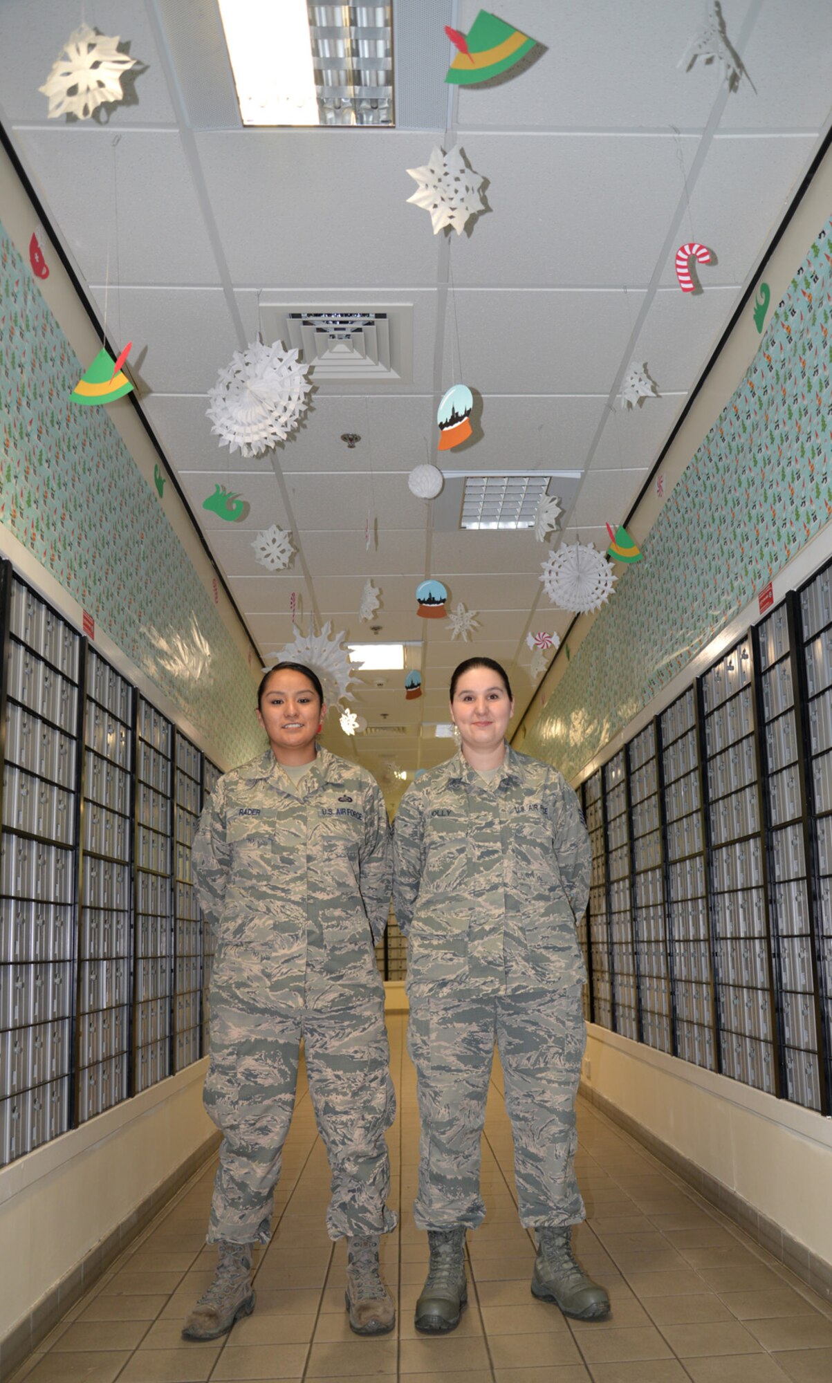 U.S. Air Force Staff Sgt. Alexandria Rader, left, 100th Communications Squadron commander’s support staff NCO in charge, and U.S. Staff Sgt. Gloria Jolly, 100th CS quality assurance evaluator, pose in front of the a themed hallway in the post office Dec. 17, 2015, on RAF Mildenhall, England. The Airmen, along with five spouses, spent many hours decorating the post office to bring holiday cheer to Team Mildenhall members. (U.S. Air Force photo by Karen Abeyasekere/Released)