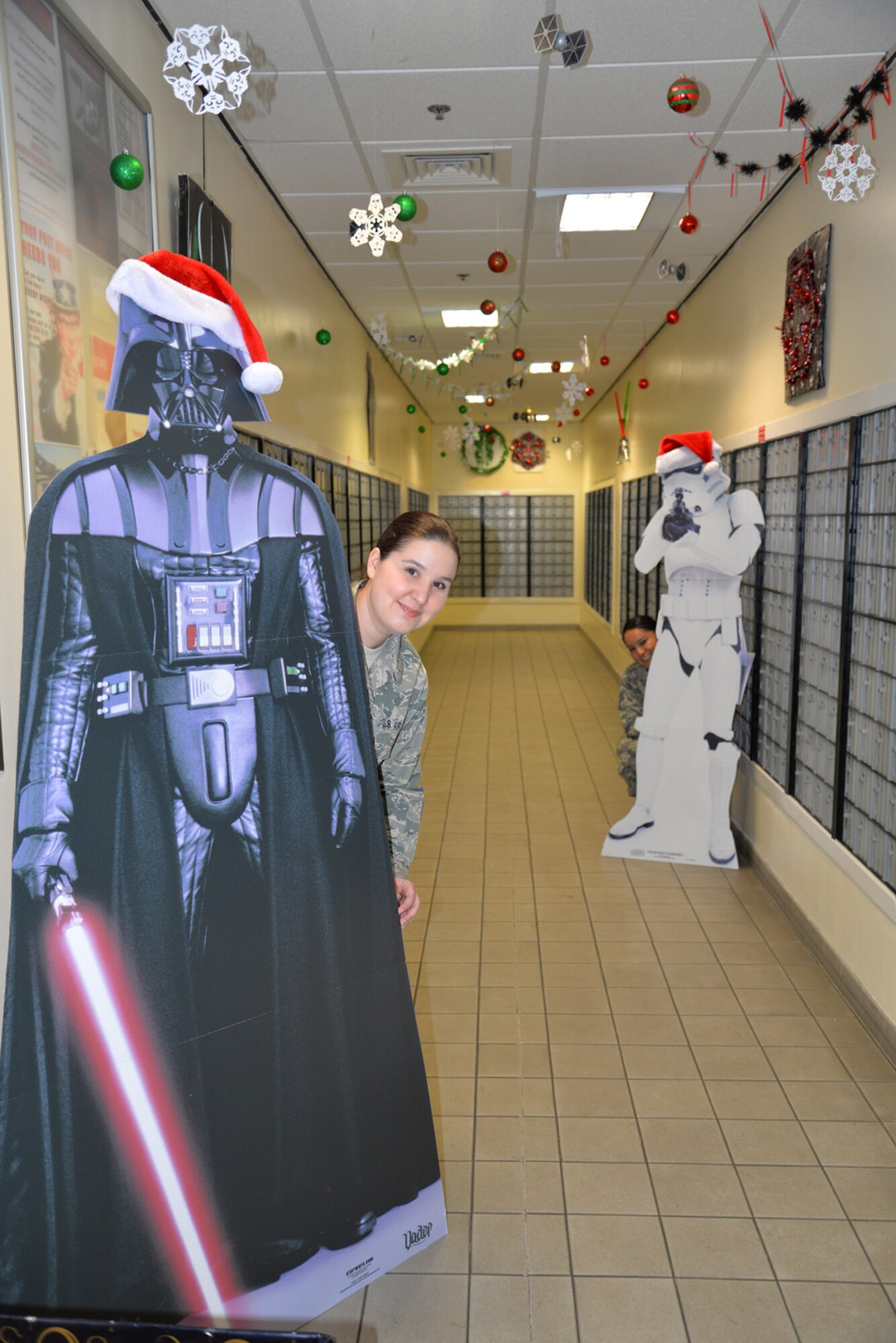 U.S. Air Force Staff Sgt. Gloria Jolly, left, 100th Communications Squadron quality assurance evaluator, and Staff Sgt. Alexandria Rader, 100th CS commander’s support staff NCO in charge, pose in the Star Wars-themed hallway in the post office Dec. 17, 2015, on RAF Mildenhall, England. This is just one of the many specially themed hallways decorated by the 100th CS Airmen and a team of spouses. (U.S. Air Force photo by Karen Abeyasekere/Released)