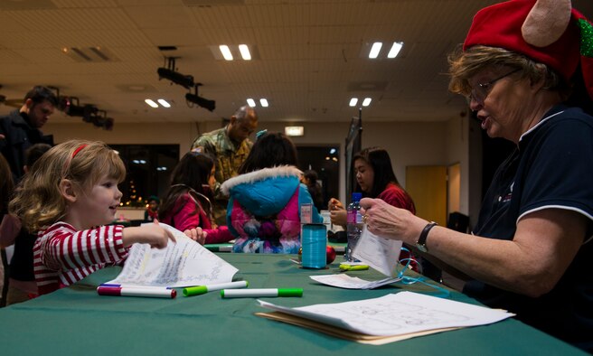 Marcie Cerf, Ramstein Community Center recreation assistant, helps a child make an elf identification badge at the Elf Boot Camp Dec. 14, 2015, at Ramstein Air Base, Germany. Children were able to make their own elf hats, elf identification badges and taste-tested cookies during the boot camp. (U.S. Air Force photo/Airman 1st Class Tryphena Mayhugh)