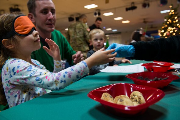 A child receives a cookie to taste-test at the Ramstein Community Center Elf Boot Camp Dec. 14, 2015, at Ramstein Air Base, Germany. The children were blind-folded and challenged to guess what type of cookie they were eating to see if they had the qualities to be an elf at the North Pole. Other activities included creating an elf identification badge, making elf hats and practicing wrapping gifts. (U.S. Air Force photo/Airman 1st Class Tryphena Mayhugh)