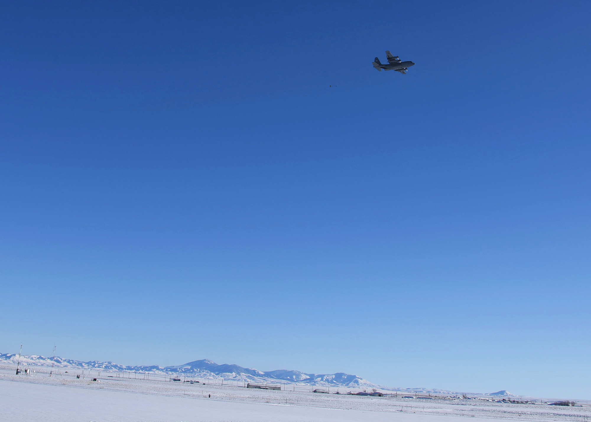 A C-130 Hercules transport from the 120th Airlift Wing, Montana Air National Guard, deploys a 15-pound sandbag connected to a five-foot parachute Dec. 17, 2015 at Malmstrom Air Force Base, Mont., to simulate an equipment drop. The exercise was the unit’s first use of the Charging Charlie training drop zone at Malmstrom, a cost-saving alternative for the 120th AW to its other training sites several hours away from Great Falls, Mont. The new drop zone was opened through a partnership between the 341st Missile Wing, the host unit at Malmstrom, and the 120th AW and reflects the total force initiative between the Air Force’s active duty and reserve components. (U.S. Air Force photo/Airman Collin Schmidt)