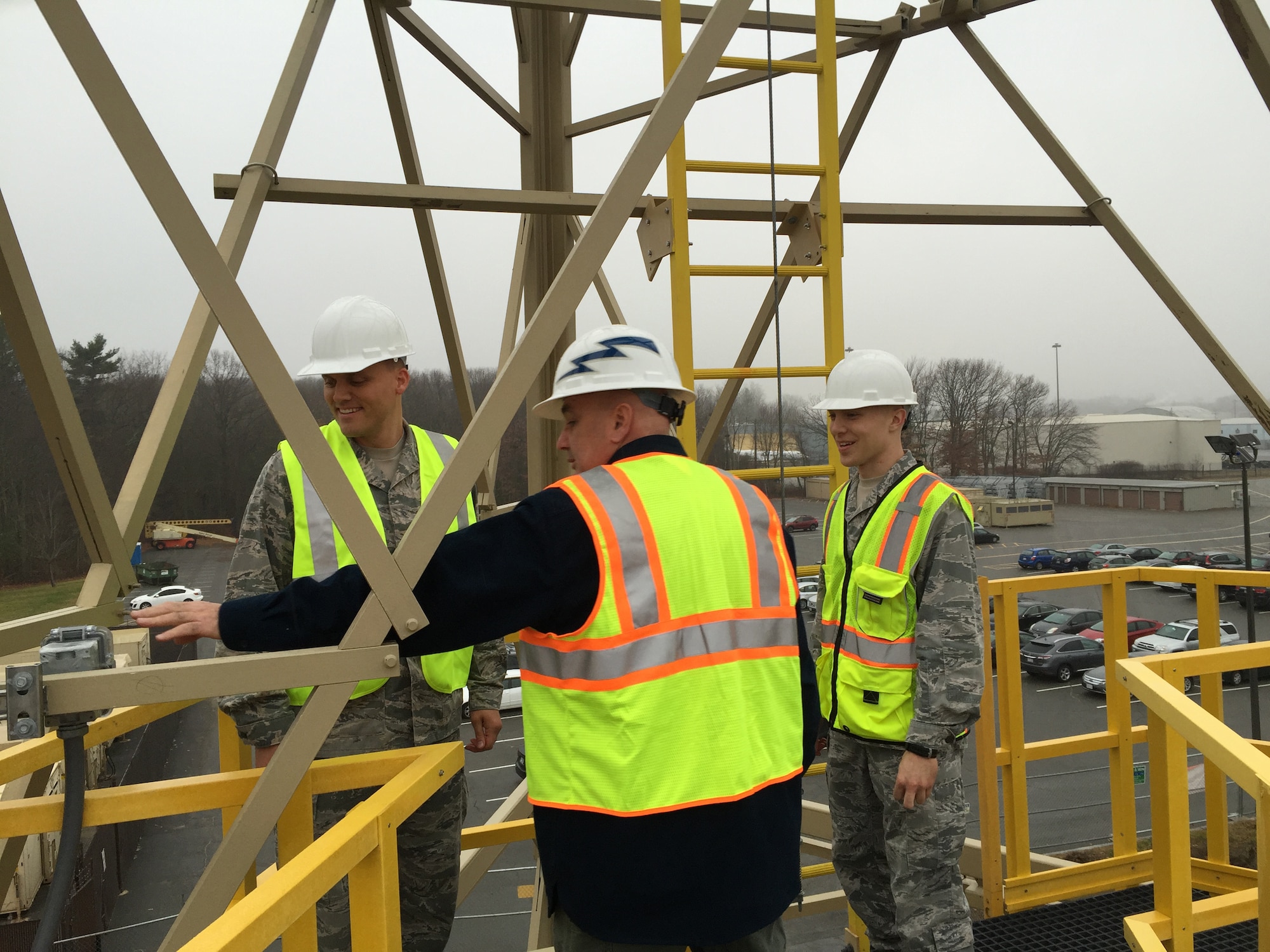 U.S. Air Force Maj. Jonathan Stueckle, Cyber Sustainment Branch chief engineer, left, Stephen O'Neil, HCIC facility manager, center, and 2nd Lt. David Beberwyk, a base Civil Engineer project manager, discuss the process of providing lighting protection to the new Hanscom Collaboration and Innovation Center radio tower, Dec. 17, 2015. The radio tower allows the testing facility to double its radio range and connect to distant military installations such as Joint Base Cape Cod. (U.S. Air Force photo by Justin Oakes)