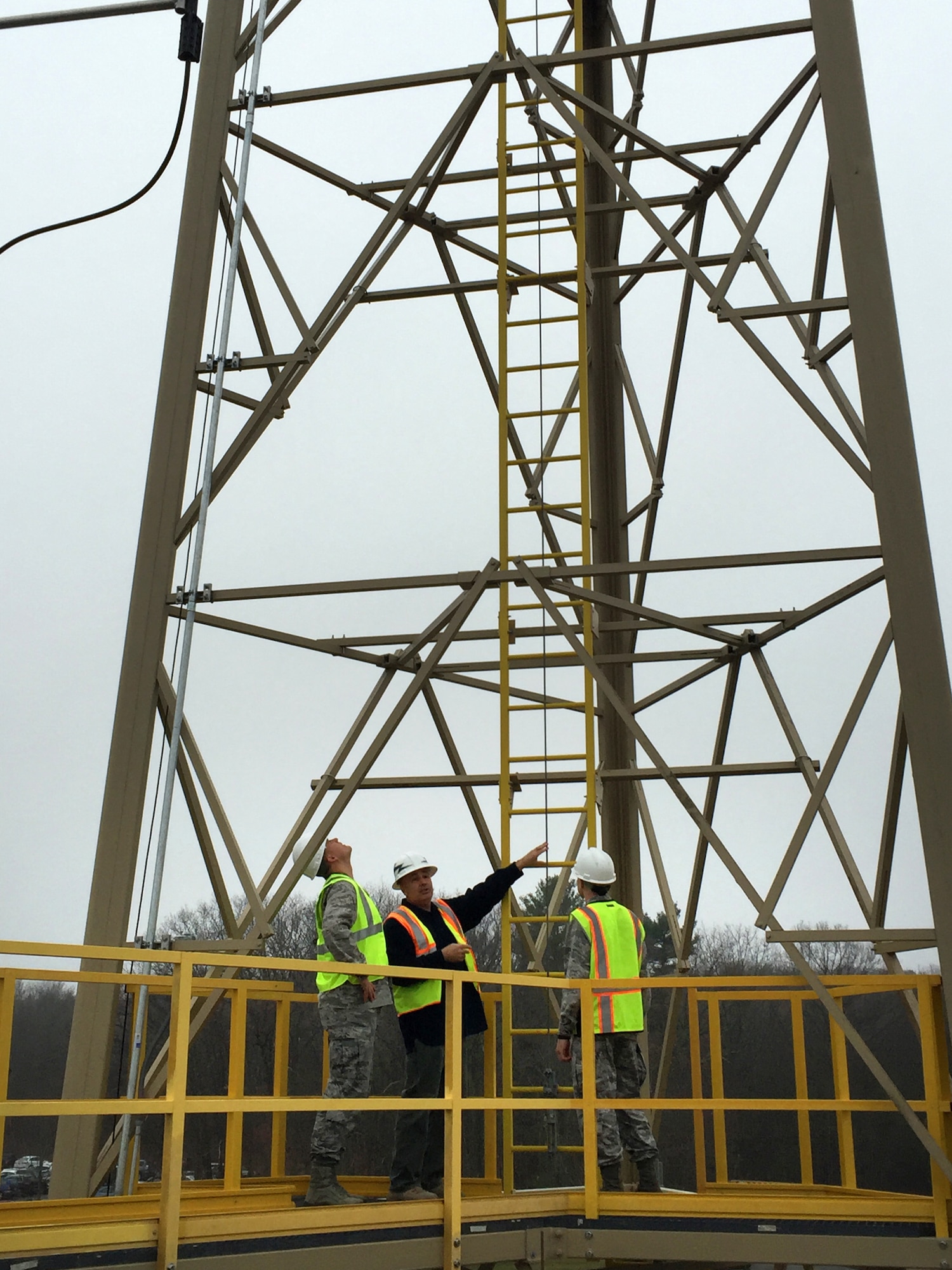 U.S. Air Force Maj. Jonathan Stueckle, left, Cyber Sustainment Branch chief engineer, Steve O'Neil, center, HCIC facility manager, and 2nd Lt. David Beberwyk, a base Civil Engineer project manager, stand on the walkway of the new Hanscom Collaboration and Innovation Center radio tower at Hanscom AFB, Mass., Dec. 17, 2015. The tower stands 120 feet tall and is made of composite material designed to reduce cost over the lifecycle of the structure. (U.S. Air Force photo by Justin Oakes)