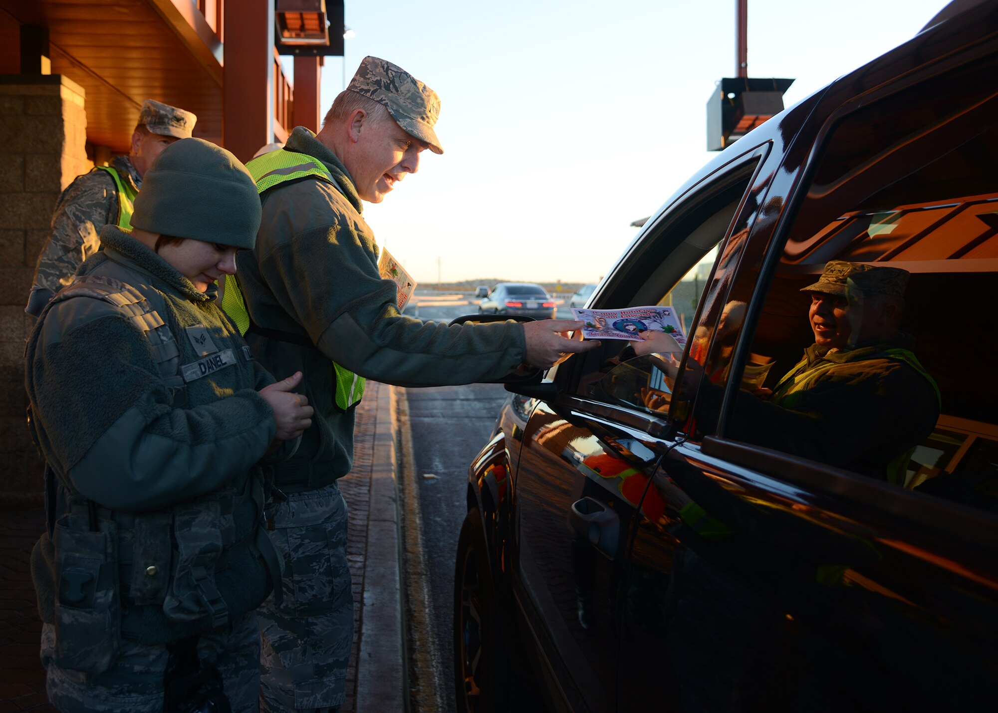Maj. Gen. David Harris, Air Force Test Center commander, wished people entering the West Gate happy holidays on their way into work as Senior Airman Helen Daniel, 412th Security Forces Squadron checked their identification. (U.S. Air Force photo by Rebecca Amber)