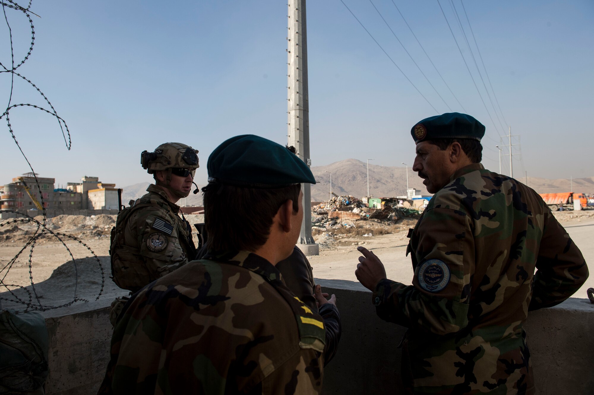 (Left) U.S Air Force Capt. Ryan Kiggins visits with Afghan Air Force soldiers near Forward Operating Base Oqab, Kabul, Afghanistan, Dec. 13, 2015. Kiggens is assigned to the Train, Advise, Assist Command-Air (TAAC-Air) security forces as an advisor. (U.S. Air Force photo by Staff Sgt. Corey Hook/Released) 