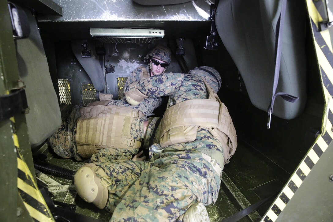 Marines with 2nd Supply Battalion, 2nd Marine Logistics Group rehearses life-saving techniques on a fellow Marine during a Humvee Egress Assistance Trainer class at Camp Lejeune, N.C., Dec. 17, 2015.  The HEAT class is designed to show Marines what to do if a vehicle rolls over during low visibility, no visibility, or experiences sideways or 180-degree rollovers.  (U.S. Marine Corps photo taken by Cpl. Alexander Mitchell/released)