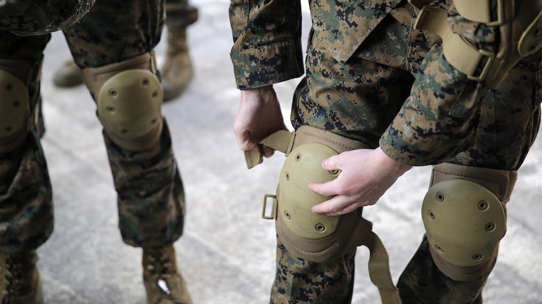 A Marine with 2nd Supply Battalion, 2nd Marine Logistics Group puts on knee pads before a Humvee Egress Assistance Trainer class at Marine Corps Base Camp Lejeune, N.C., Dec. 17, 2015. The HEAT class is designed to show Marines what to do if a vehicle rolls over during low visibility, no visibility, or experiences sideways or 180-degree rollovers.  
