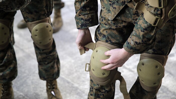A Marine with 2nd Supply Battalion, 2nd Marine Logistics Group puts on knee pads before a Humvee Egress Assistance Trainer class at Marine Corps Base Camp Lejeune, N.C., Dec. 17, 2015. The HEAT class is designed to show Marines what to do if a vehicle rolls over during low visibility, no visibility, or experiences sideways or 180-degree rollovers.  
