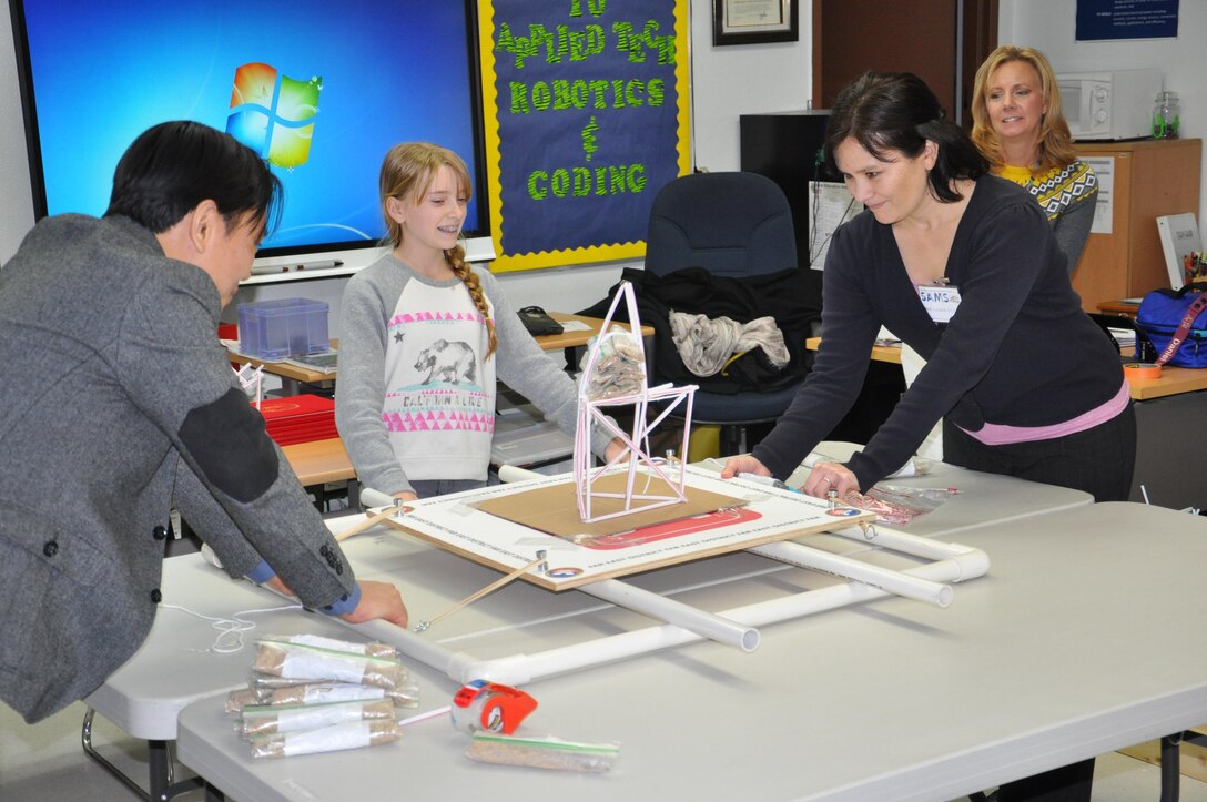 Seoul American Middle School student Hannah Sullivan prepares to see if her tower can withstand the force of an earthquake as Far East District science, technology, engineering and math coordinator Pam Lovasz (right), Seoul American Middle School applied technology teacher Kelly Brock (far right) and district engineering division design branch chief Son Ha (left) look on. 