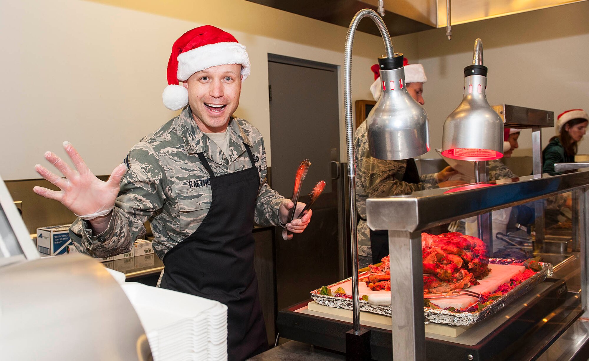 Chief Master Sgt. Jason Raether, National Air and Space Intelligence Center acting command chief, waves at the camera during the 88th Air Base Wing’s annual holiday meal at the Pitsenbarger Dining Facility at Wright-Patterson Air Force Base, Ohio, Dec. 16, 2015.  Each year the dining facility staff prepares a special Holiday themed dinner for patrons. Throughout the evening several Wright-Patterson AFB senior leaders serve the dinner to Airmen as a gesture of appreciation for their hard work. (U.S. Air Force photo by Tech. Sgt. Eunique P. Thomas)