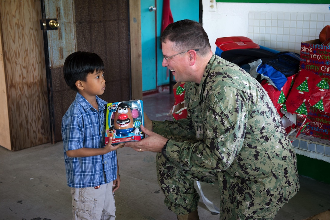 U.S. Navy Lt. Andrew Forester, Naval Base Guam chaplain assigned to Commander, Task Force 75, gives a toy to a child for Operation Christmas Drop at Saipan, Dec. 20, 2015. Operation Christmas Drop is the longest-running humanitarian airlift operation in the world, and the longest ongoing U.S. military operation. In addition to delivering critical supplies and holiday gifts to the people of the Pacific Islands, Christmas Drop trains U.S. service members to airlift material to remote locations. CTF 75 is the primary expeditionary task force responsible for the planning and execution of coastal riverine operations, explosive ordnance disposal, diving engineering and construction and underwater construction in the U.S. 7th Fleet area of responsibility. U.S. Navy photo by Petty Officer 1st Class Ace Rheaume