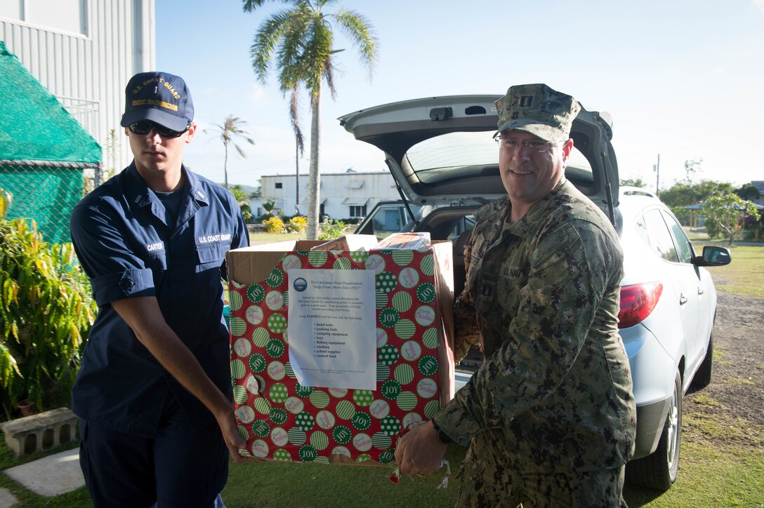 U.S. Navy Lt. j. g. Harrison Carter, left, assigned to U.S. Coast Guard Cutter Washington and U.S. Navy Lt. Andrew Forester, Naval Base Guam chaplain assigned to Commander, Task Force 75, carries supplies for delivery to Tinian for Operation Christmas Drop at Tinian, Dec. 19, 2015. Operation Christmas Drop is the longest-running humanitarian airlift operation in the world, and the longest ongoing U.S. military operation. In addition to delivering critical supplies and holiday gifts to the people of the Pacific Islands, Christmas Drop trains U.S. service members to airlift material to remote locations. CTF 75 is the primary expeditionary task force responsible for the planning and execution of coastal riverine operations, explosive ordnance disposal, diving engineering and construction and underwater construction in the U.S. 7th Fleet Area of Responsibility. U.S. Navy photo by Petty Officer 1st Class Ace Rheaume
