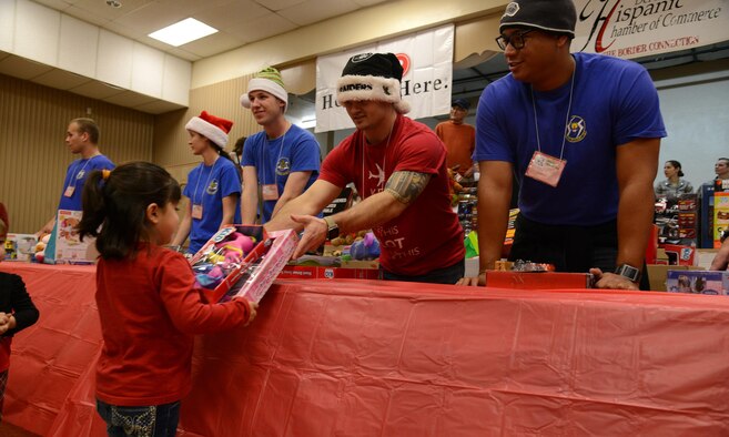 Captain Mathew Crippes, 85th Flying Training Squadron B-flight instructor pilot, gives a gift to a local child during the annual Niños Navideños event at the Civic Center in Del Rio, Texas, Dec. 19, 2015. More than 20 Laughlin members volunteered to hand out toys to local youth. (U.S. Air Force photo by Airman 1st Class Ariel D. Partlow)