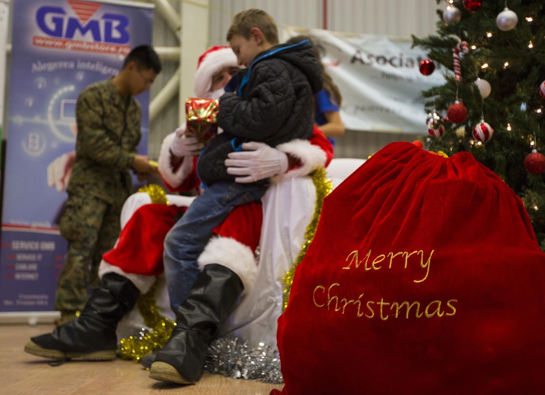 A Romanian child sits on Santa's lap during a Christmas celebration with U.S. Marines, sailors and soldiers on Mihail Kogalniceanu Air Base, Romania, Dec. 19, 2015. U.S. Marine Corps photo by Lance Cpl. Melanye E. Martinez