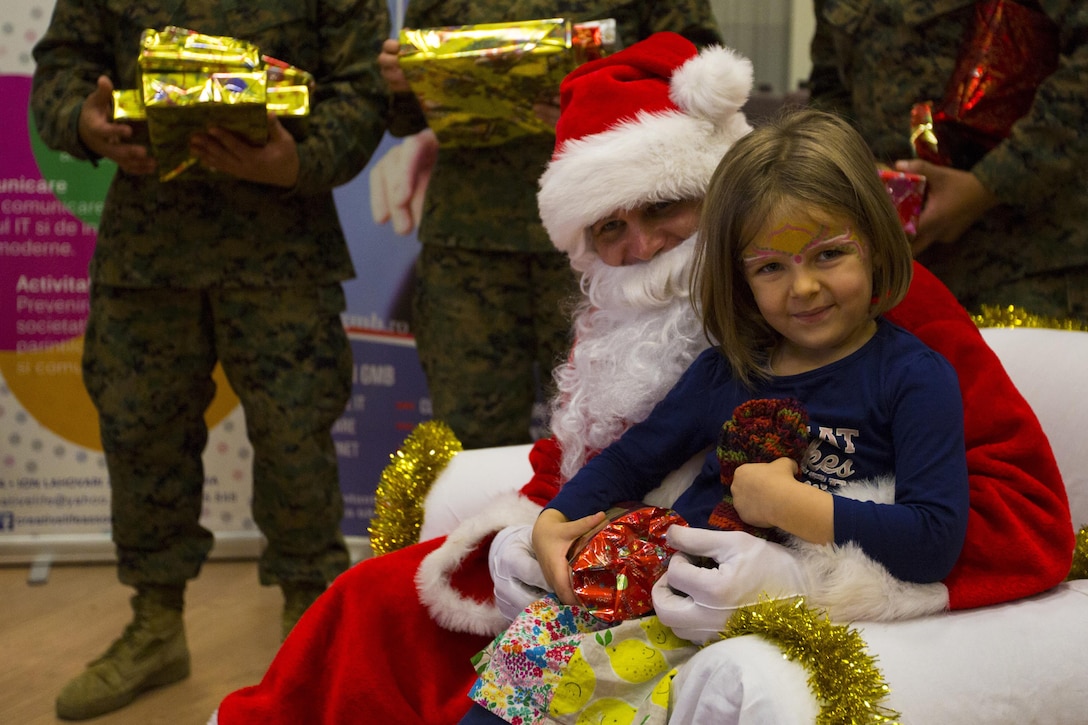 A Romanian girl sits with Santa as U.S. Marines, sailors and soldiers celebrate Christmas with children on Mihail Kogalniceanu Air Base, Romania, Dec. 19, 2015. U.S. Marine Corps photo by Lance Cpl. Melanye E. Martinez