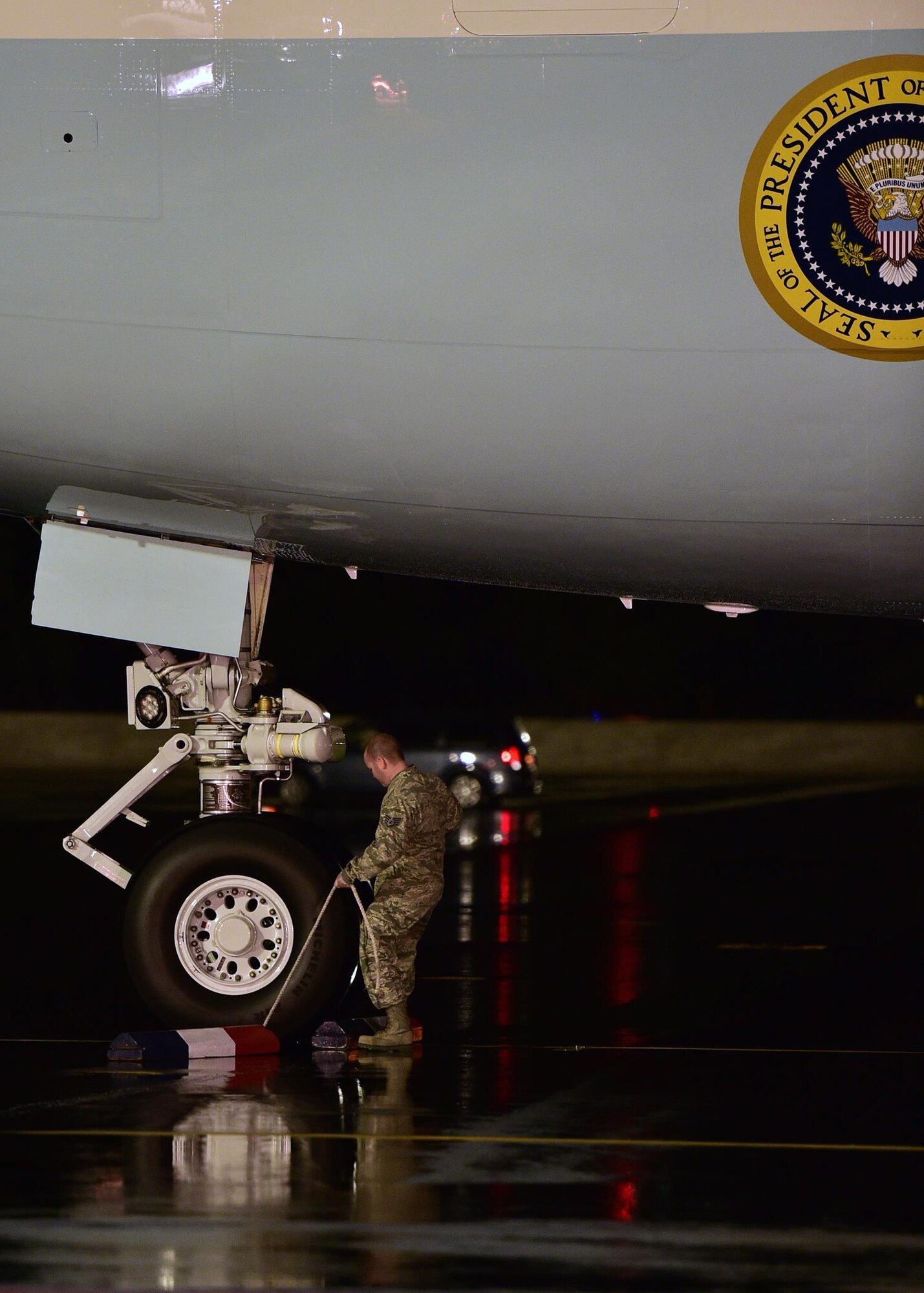 Staff Sgt. Joseph Stamps, from 15th Maintenance Squadron, places chocks on the front landing gear of Air Force one as the ceremonial chocker on Joint Base Pearl Harbor-Hickam, Hawaii, Dec. 18 2015. The First Family passed through JBPHH as they begin their annual holiday vacation. Airmen from the 15th Wing assisted with planning and preparation of the First Family’s arrival. (U.S. Air Force photo by Tech. Sgt. Aaron Oelrich/Released)