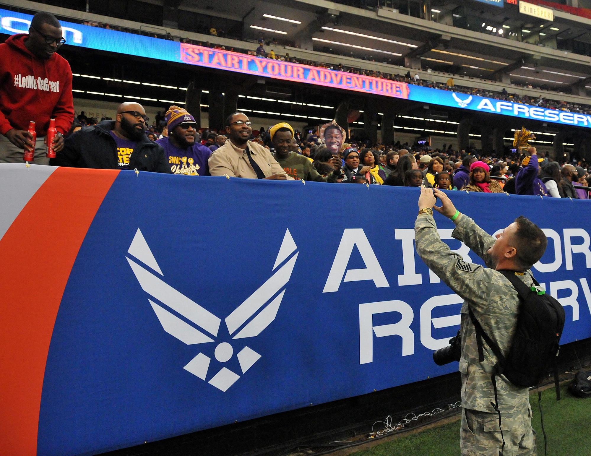 Master Sgt. Chance Babin, Air Force Reserve Command public affairs broadcaster, takes a picture for a group of spectators at the inaugural Air Force Reserve Celebration Bowl Dec. 19 at the Georgia Dome in Atlanta. The spectators asked if he would use their cellular phone to take their picture. (U.S. Air Force photo/Senior Airman Andrew Park)