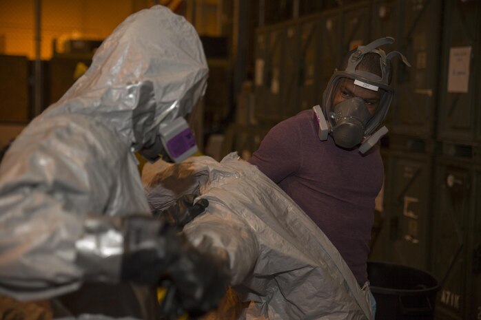 A Marine from Marine Wing Support Squadron 171 assists Sgt. Deedmund Nettles, left, food service specialist with MWSS-171, in removing his personal protective equipment during Hazardous Waste Operations and Emergency Response training at Marine Corps Air Station Iwakuni, Japan, Dec. 18, 2015. The course covered topics such as the hazards associated with working around chemicals, how to locate information on different chemicals, and the four aspects of planning and organizing a hazardous waste site, which are organizational structure, work plan, safety meetings and inspections. This training provided Marines with the proper knowledge to identify contain and clean up hazardous materials.