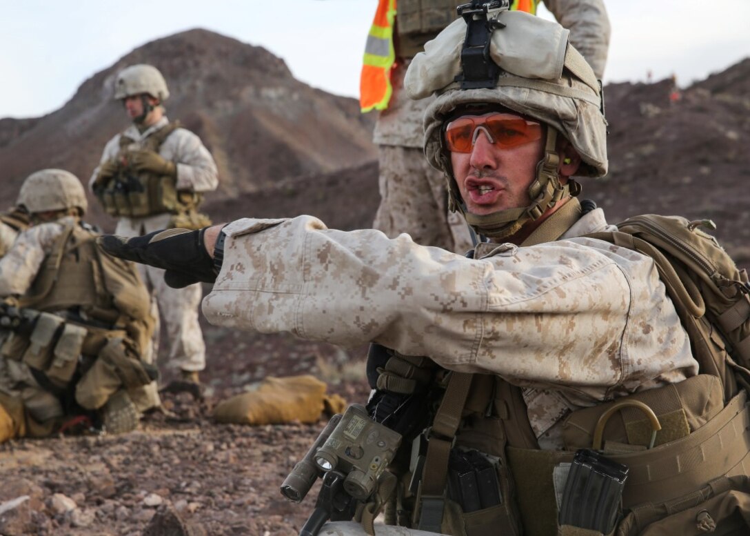 Cpl. Garrett Schroll gives the traverse hand-and-arm signal to his team during the company supported, live-fire assault portion of a Marine Corps Combat Readiness Evaluation at Marine Corps Air Ground Combat Center Twentynine Palms, Calif., Dec. 6, 2015. The purpose of a MCCRE is to evaluate Marines’ collective performance in specific mission requirements that will prepare them for their upcoming deployment rotation. Schroll is a machine gunner, with 2nd Battalion, 7th Marine Regiment, 1st Marine Division. (U.S. Marine Corps photo by Lance Cpl. Devan K. Gowans)