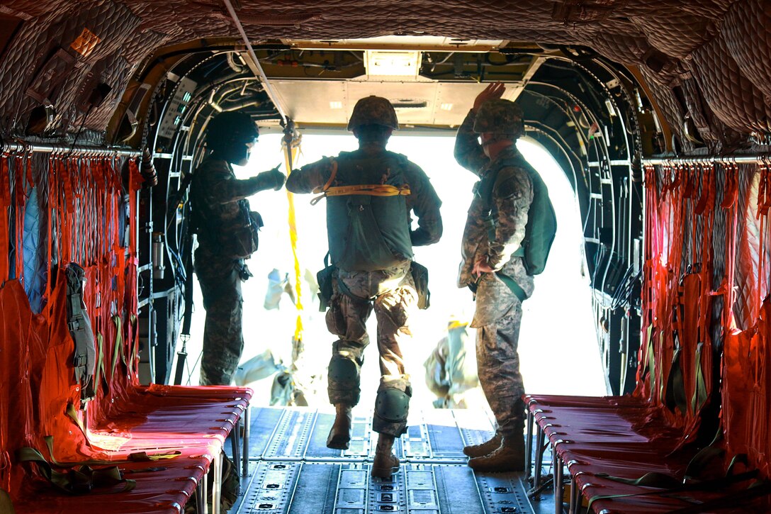 An Army paratrooper exits a CH-47 Chinook during an airborne jump over Sicily drop zone on Front Bragg, N.C., Dec. 15, 2015. The paratrooper is assigned to the 82nd Airborne Division. U.S. Army photo by Staff Sgt. Christopher Freeman