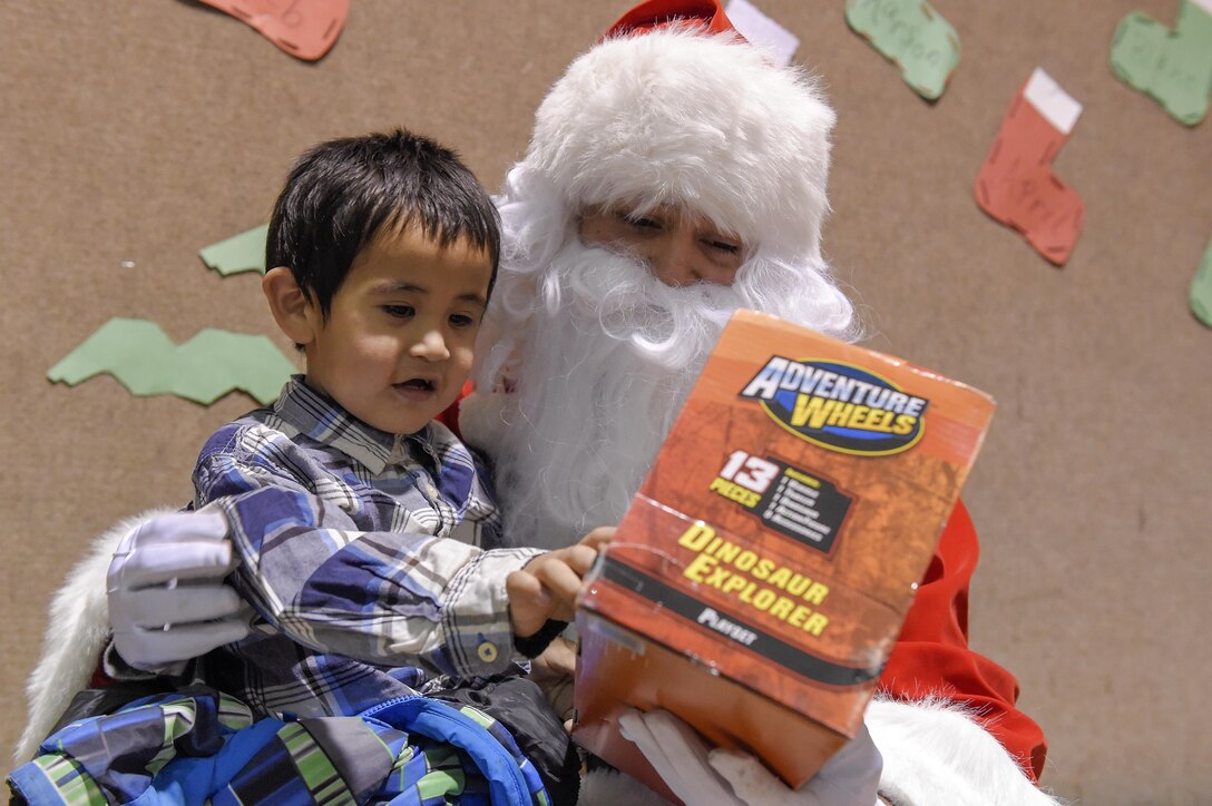 Santa Claus, played by Marine Corps Sgt. Mauricio Sandoval, gives a toy to a little boy during a Toys for Tots event in Nikolai, Alaska, Dec. 11, 2015. Sandoval is assigned to Delta Company, 4th Law Enforcement Battalion. U.S. Air Force photo by Alejandro Pena