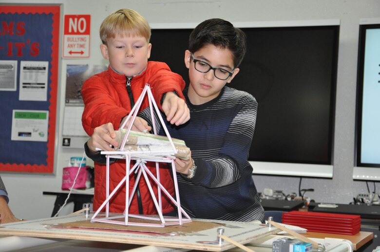 Seoul American Middle School students Charles Floyd (right) and John Shirley strategically place sandbags to the tower they created during an earthquake tower challenge competition at Seoul American Middle School Dec. 16, 2015.