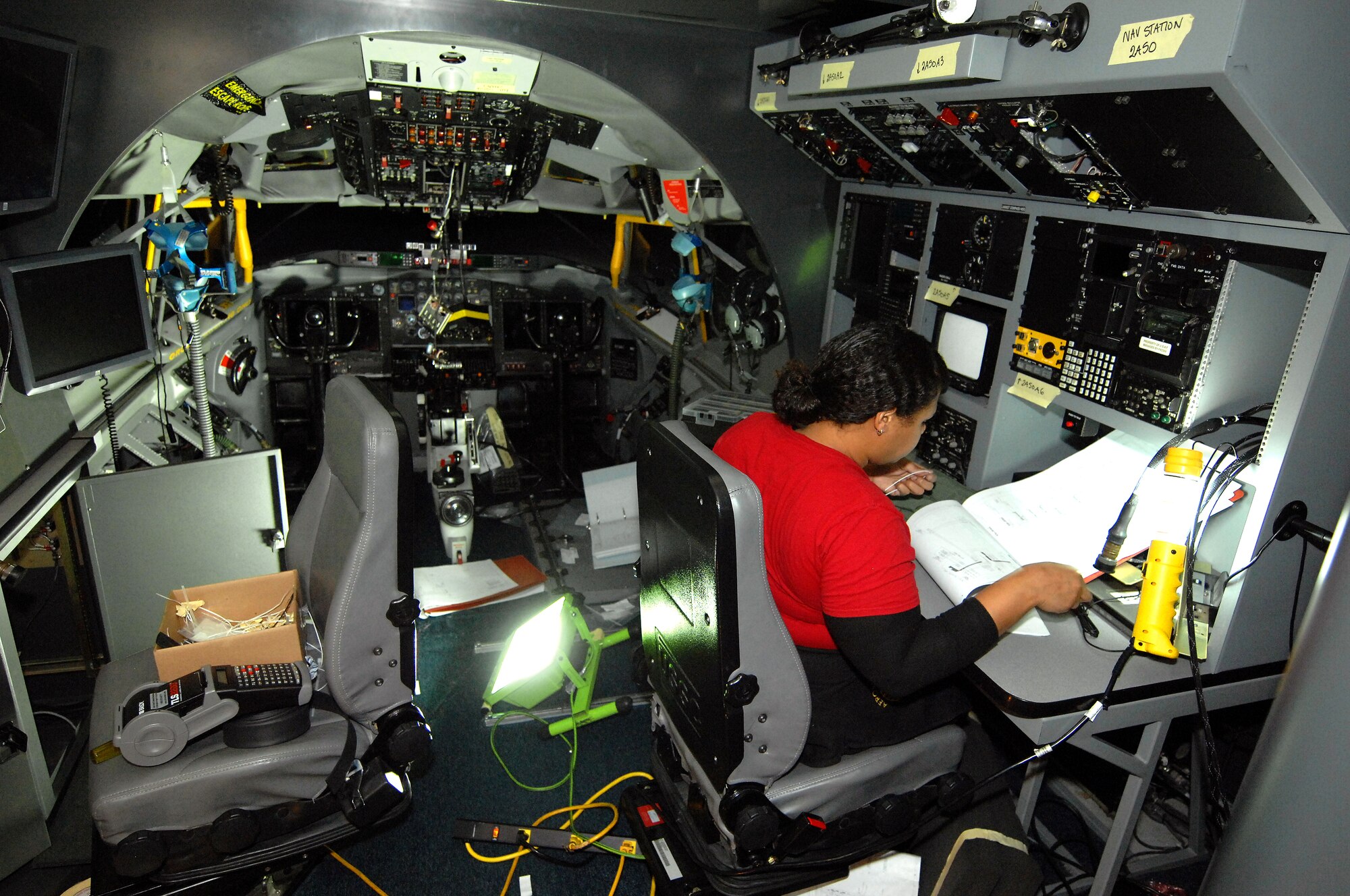 Jennifer Sanchez, an aircraft mechanic and electrician with L-3 Communications, examines a wiring diagram while installing upgrade equipment on board the Offutt Flight Trainer #3 Dec. 11 at Offutt Air Force Base, Neb. Sanchez and a team of engineers, mechanics and electricians from L-3 Communications were performing upgrades to the flight simulator that mirrors the RC-135 aircraft. (U.S. Air Force photo by Delanie Stafford/Released)