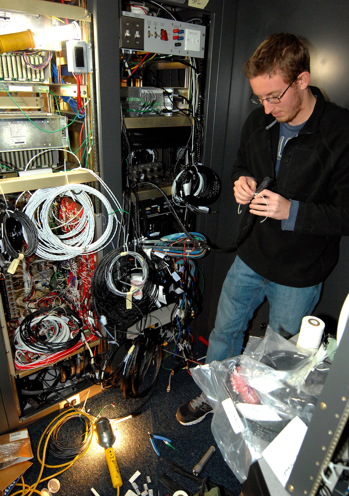 Jeremy Etlicher, an aircraft mechanic and electrician with L-3 Communications, connects wiring while installing Fiber Optic Ring Communication Equipment on board the Offutt Flight Trainer #3 Dec. 11 at Offutt Air Force Base, Neb. Etlicher and a team of engineers, mechanics and electricians from L-3 Communications were performing upgrades to the flight simulator that mirrors the RC-135 aircraft. (U.S. Air Force photo by Delanie Stafford/Released)