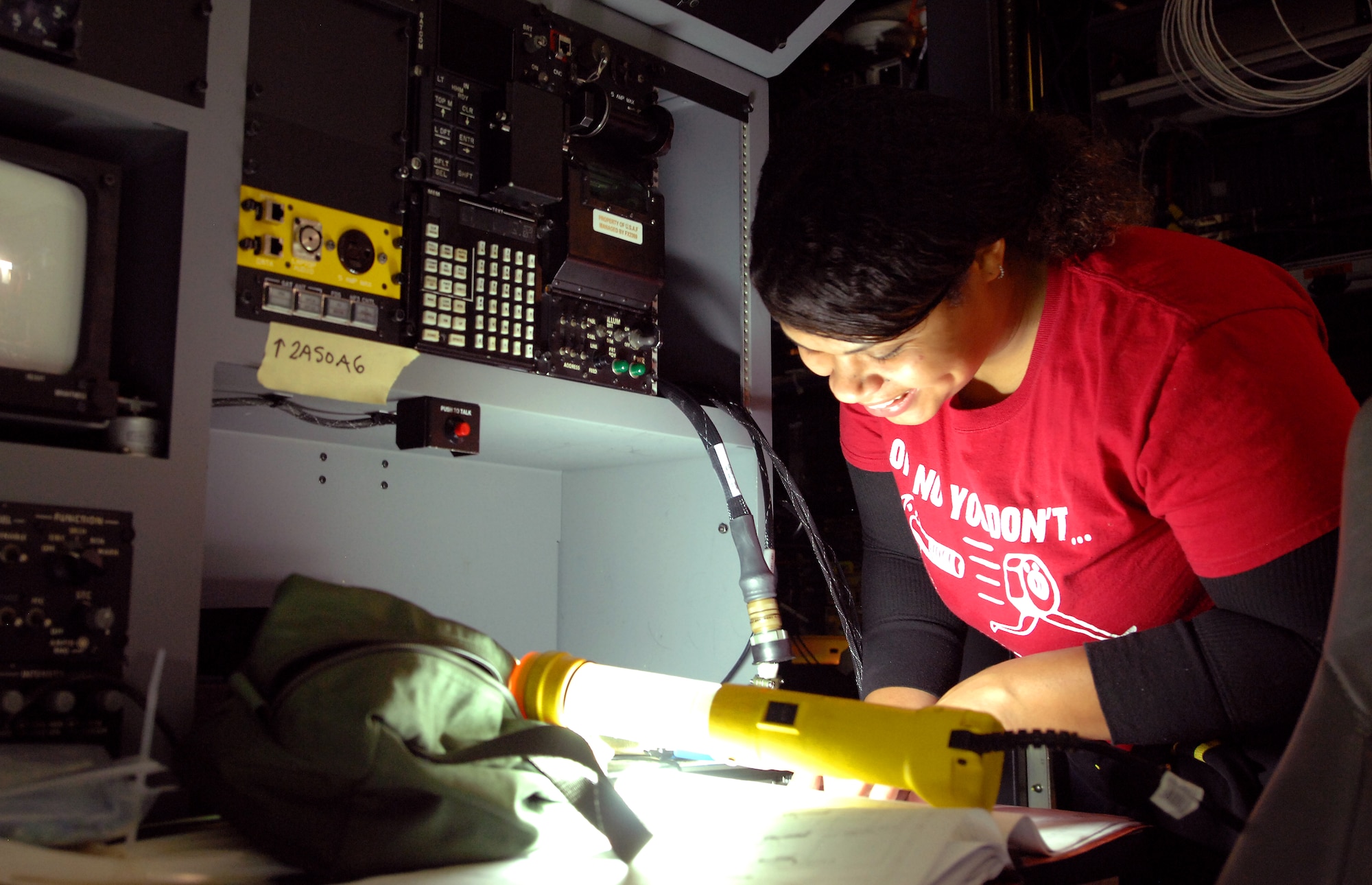 Jennifer Sanchez, an aircraft mechanic and electrician with L-3 Communications, examines a wiring diagram while installing upgrade equipment on board the Offutt Flight Trainer #3 Dec. 11 at Offutt Air Force Base, Neb. Sanchez and a team of engineers, mechanics and electricians from L-3 Communications were performing upgrades to the flight simulator that mirrors the RC-135 aircraft. (U.S. Air Force photo by Delanie Stafford/Released)