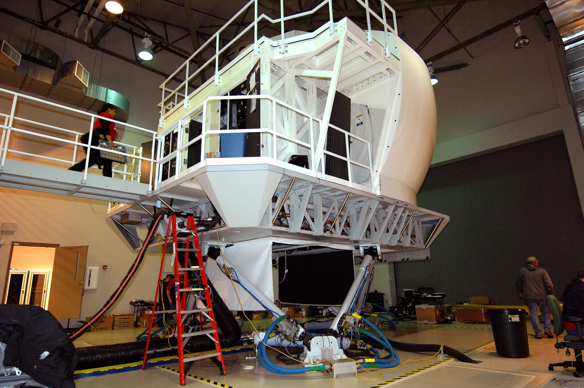 Jennifer Sanchez, an aircraft mechanic and electrician with L-3 Communications, boards Offutt Flight Trainer #3 Dec. 11 at Offutt Air Force Base, Neb. Sanchez and a team of engineers, mechanics and electricians from L-3 Communications are installing upgrades to the flight simulator that mirrors the RC-135 aircraft. (U.S. Air Force photo by Delanie Stafford/Released)