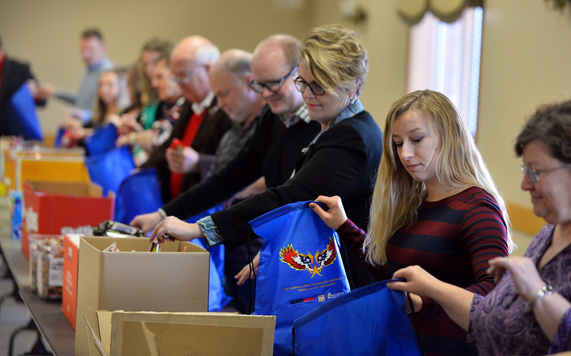 An assembly line of volunteers fill and pass blue bags that will be donated to the Airmen living in the Offutt Air Force Base dormitories this holiday season at the Bellevue Fire House on Dec. 17, Bellevue Neb.  Offutt Air Force Base has long standing ties with the local community.  (U.S. Air Force photo by Josh Plueger)