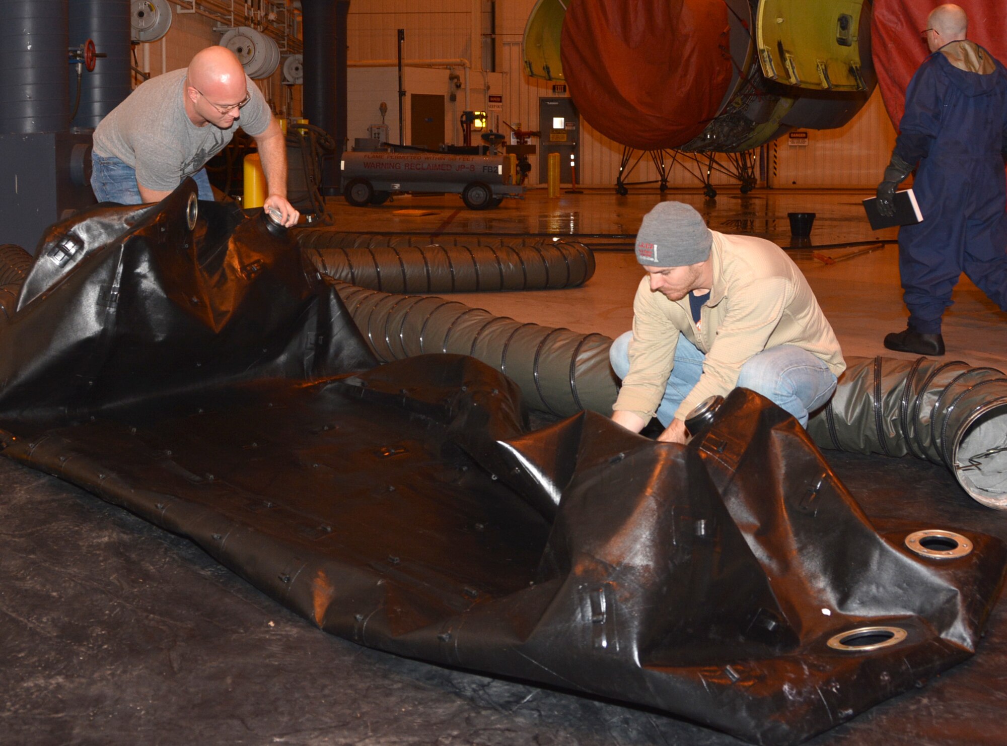 Staff Sgt. Sean Carter, left, and Tech. Sgt. Joshua Green, right, fuel systems technicians with the 507th Maintenance Squadron, install pressure plates on an empty fuel cell taken from a KC-135R center wing tank in order to check the cell for a possible leak Dec. 15, 2015, at Tinker Air Force Base, Okla. The removable fuel cells are made of nylon fabric that is in some instances less than 1/16 of an inch thick yet can hold seven tons of fuel. The KC-135R is capable of transferring more fuel in eight minutes than a gas station could pump in 24 hours. (U.S. Air Force photo/Tech. Sgt. Lauren Gleason)