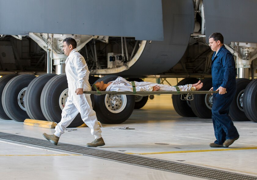 Senior Airman Eric Garcia and Tech. Sgt. Jason Rachwitz, 433rd Maintenance Squadron aircraft fuel systems technicians, carry a litter outside the hanger as they wait for emergency services to arrive Dec. 17, 2015 at Joint Base San Antonio-Lackland, Texas. The annual exercise is graded for extraction protocol, execution time, and safety. This year the Airmen completed the exercise in record time, 3 minutes and 15 seconds. (U.S. Air Force photo by Benjamin Faske) (released)