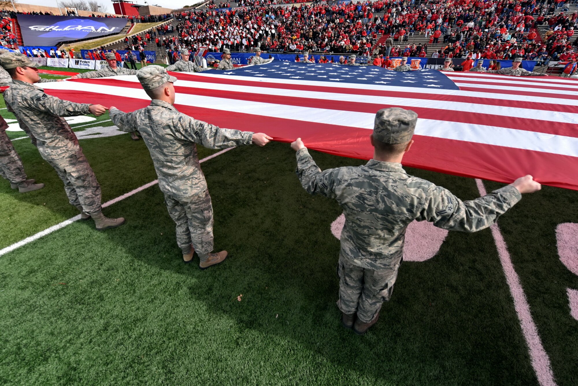 Volunteers from Kirtland unfurl a large flag at the UNM Gildan Bowl Dec. 19. (Photo by Ken Moore)