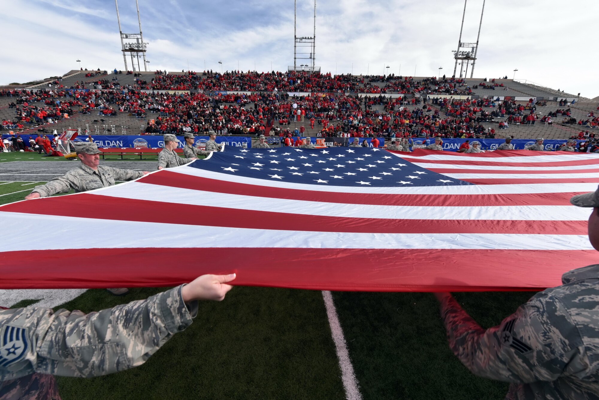 Volunteers from Kirtland unfurl a large flag at the UNM Gildan Bowl Dec. 19. (Photo by Ken Moore)