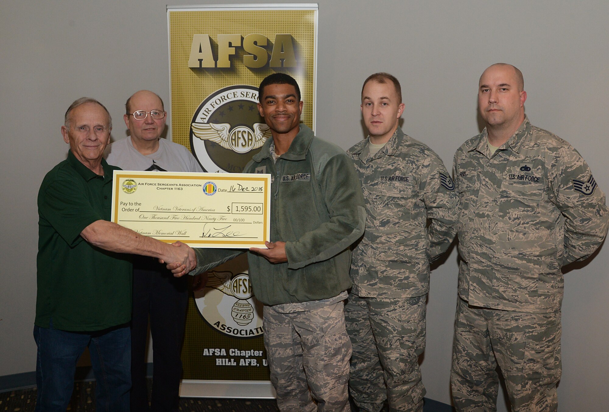 Air Force Sergeant's Association (AFSA) Chapter1163 members Tech. Sgt. Michael Corum, Tech. Sgt. Aaron Haviland and Staff Sgt. Jacob Reid present a check to Vietnam Veterans of America members Dennis Howland, far left, and David Wilson Dec. 16 at Hill Air Force Base, Utah. The AFSA chapter raised funds during POW/MIA Week by selling ribbons, bracelets and T-shirts along with sponsoring a 5K run in Layton, Utah. The base chapter chose the Vietnam Veterans of America as recipients of all the proceeds to help fund the Vietnam Memorial replica planned for Layton Commons Park. (U.S. Air Force photo/Alex R. Lloyd)