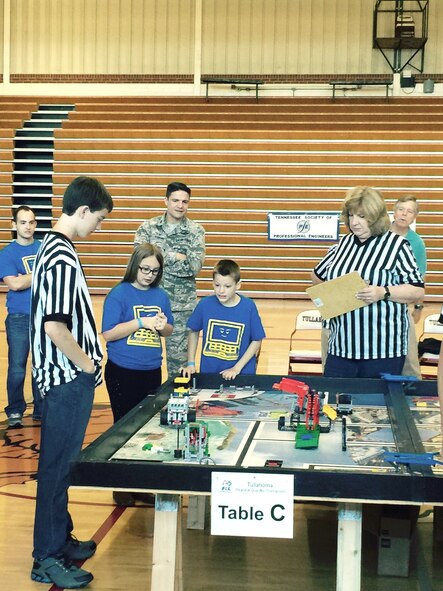 The Regional Qualifying Tournament for the FIRST® LEGO® League of Middle Tennessee was held Dec. 5 at Tullahoma High School. Twenty-five teams across the region attended and 15 of them will go on to compete at the Regional FLL Tournament in February at Tennessee Tech University. College Street Elementary students Cole Fowler and Natalee Putman watch their robot perform its programmed tasks. The students’ coach Capt. Chance Johnson (back left), AEDC Commander Col. Rodney Todaro (back center), and AEDC STEM Educational Outreach Specialist Jere Matty (back right), look on as the competition judges take notes. (U.S. Air Force photo/Holly Fowler)