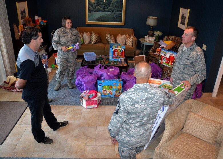 Col. Dan Merry, Air Force Mortuary Affairs Operations commander, Chief Master Sgt. Rabin Ramsook, AFMAO chief enlisted manager, and Tech. Sgt. Dorothy Whitfield, Fisher House for Families of the Fallen, NCO in charge, thank Bill Flanders, USO Delaware operations supervisor, for new toys donated by the USO Dec. 9, 2015, for the Fisher House for Families of the Fallen, Dover Air Force Base, Del. The USO donation refreshed the toy selection for families of the fallen who travel to Dover to witness the dignified transfer of a loved one. (U.S. Air Force photo/Senior Airman Robert Gunn/Released)