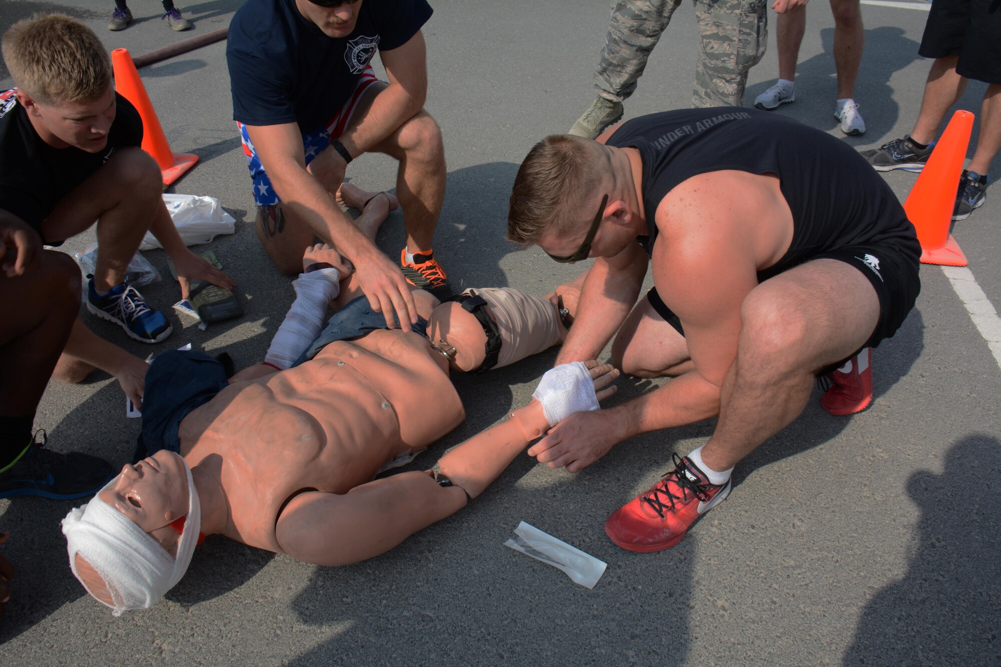 Tech. Sgt. Brent Watkins, 379th Expeditionary Civil Engineer Squadron station captain, bandages a hand wound on a dummy while his teammates look on during the fitness challenge of the annual Battle of the Badges competition at Al Udeid Air Base, Qatar Dec. 21. The competition consisted of numerous events over four days including firefighter, medical and security forces career field challenges. The fitness challenge closed the event. The 379 ECES fire team took first place in the competition. (U.S. Air Force photo by Tech. Sgt. James Hodgman/Released) 