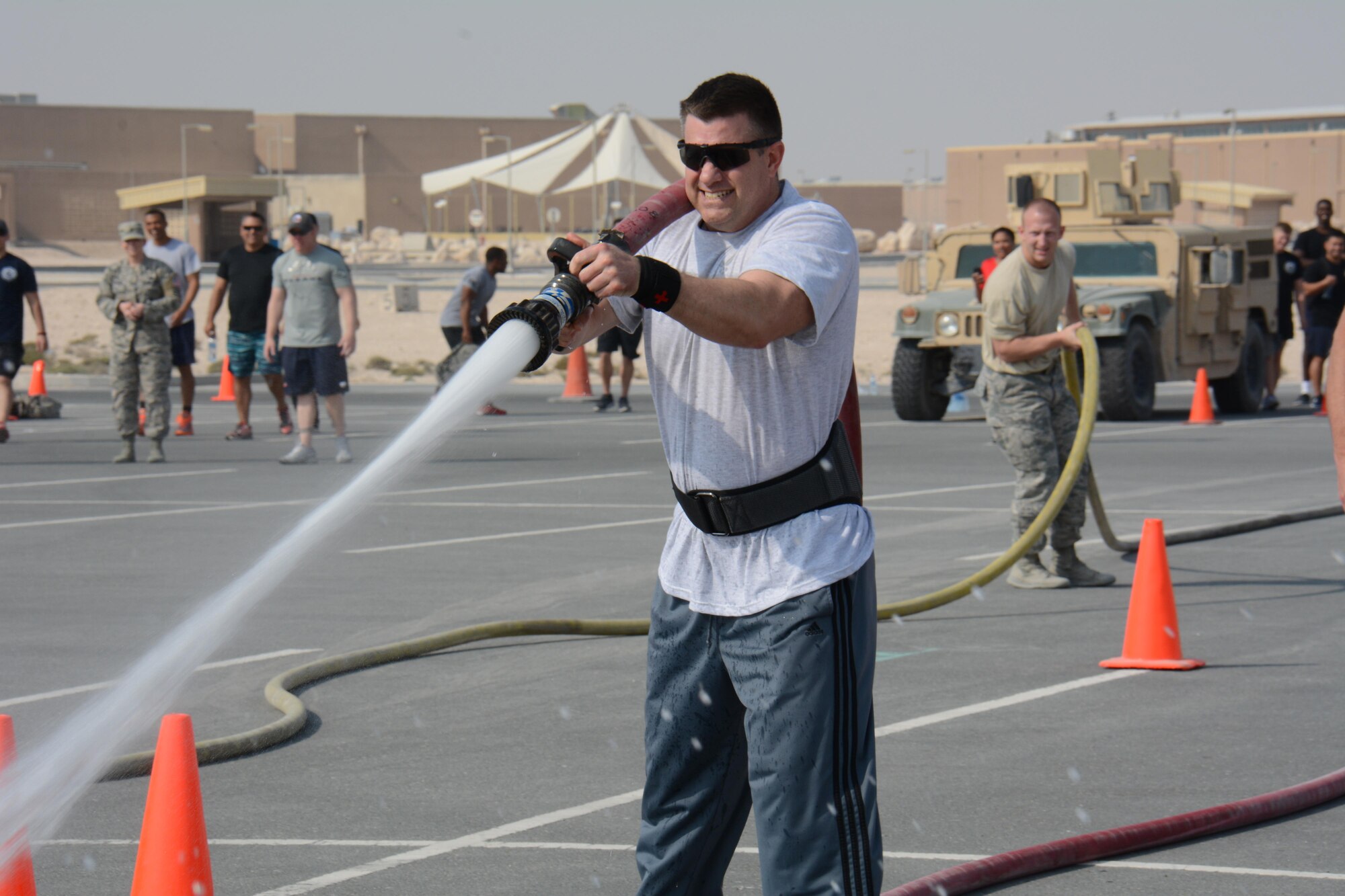 Capt. James Taylor, 379th Medical Operations Squadron nurse, uses a fire hose to knock down three cones during the annual Battle of the Badges competition at Al Udeid Air Base, Qatar Dec. 21. The competition consisted of numerous events over four days including firefighter, medical and security forces career field challenges, as well as a fitness challenge. The 379 ECES fire team took first place in the competition. (U.S. Air Force photo by Tech. Sgt. James Hodgman/Released) 