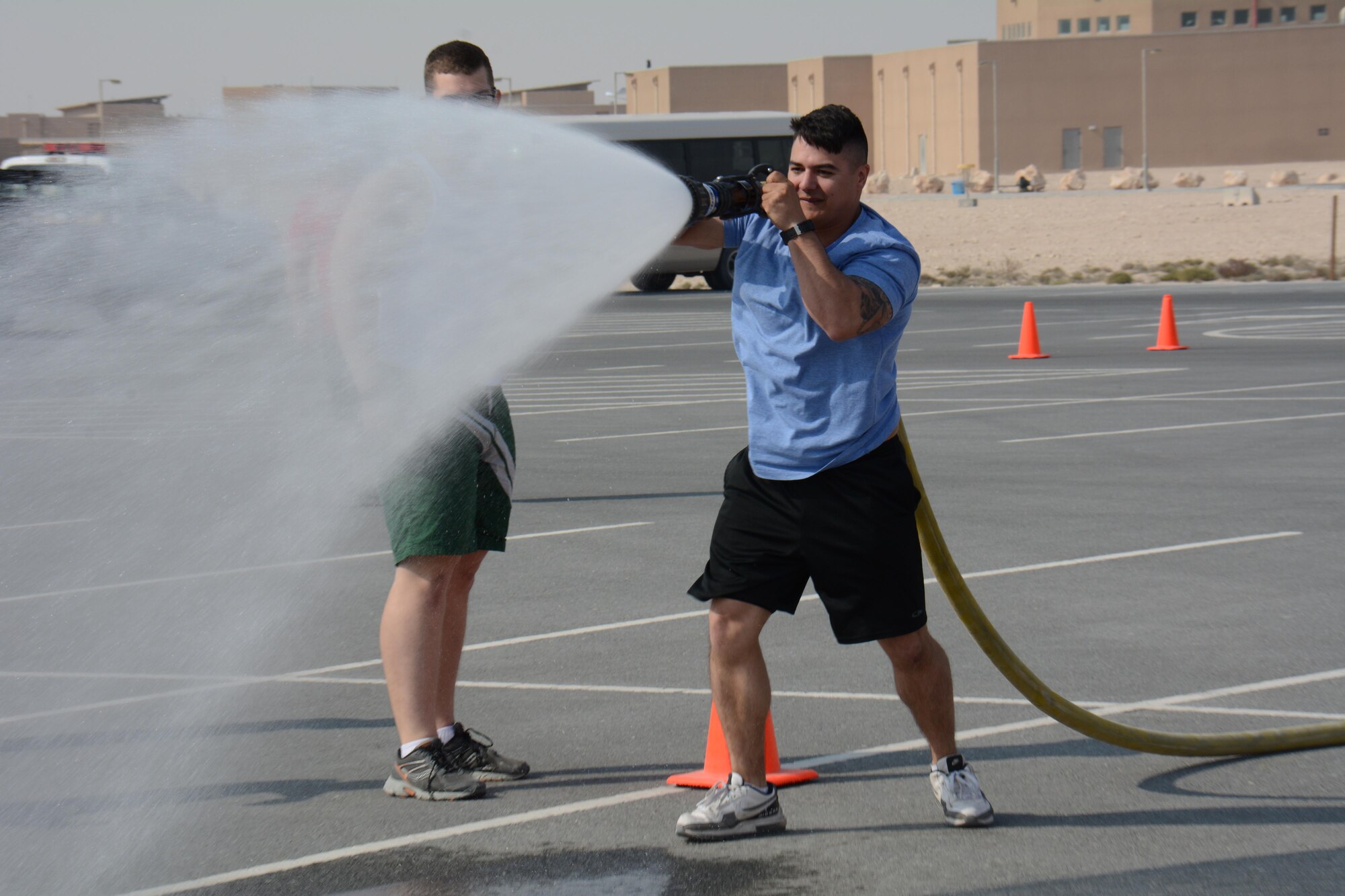 Staff. Sgt. Robert Connolly, 379th Expeditionary Security Forces Squadron Emergency Communications Center controller, uses a fire hose to knock down three cones during the annual Battle of the Badges competition at Al Udeid Air Base, Qatar Dec. 21. The competition consisted of numerous events over four days including firefighter, medical and security forces career field challenges, as well as a fitness challenge. The 379 ECES fire team took first place in the competition. (U.S. Air Force photo by Tech. Sgt. James Hodgman/Released) 
