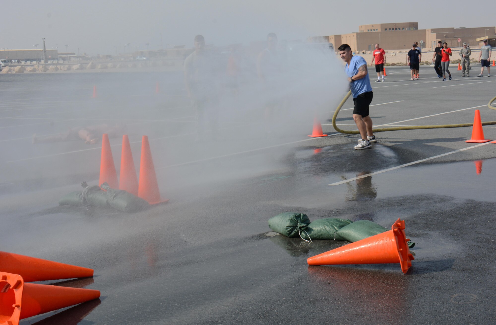 Staff. Sgt. Robert Connolly, 379th Expeditionary Security Forces Squadron Emergency Communications Center controller, uses a fire hose to knock down three cones during the annual Battle of the Badges competition at Al Udeid Air Base, Qatar Dec. 21. The competition consisted of numerous events over four days including firefighter, medical and security forces career field challenges, as well as a fitness challenge. The 379 ECES fire team took first place in the competition. (U.S. Air Force photo by Tech. Sgt. James Hodgman/Released) 