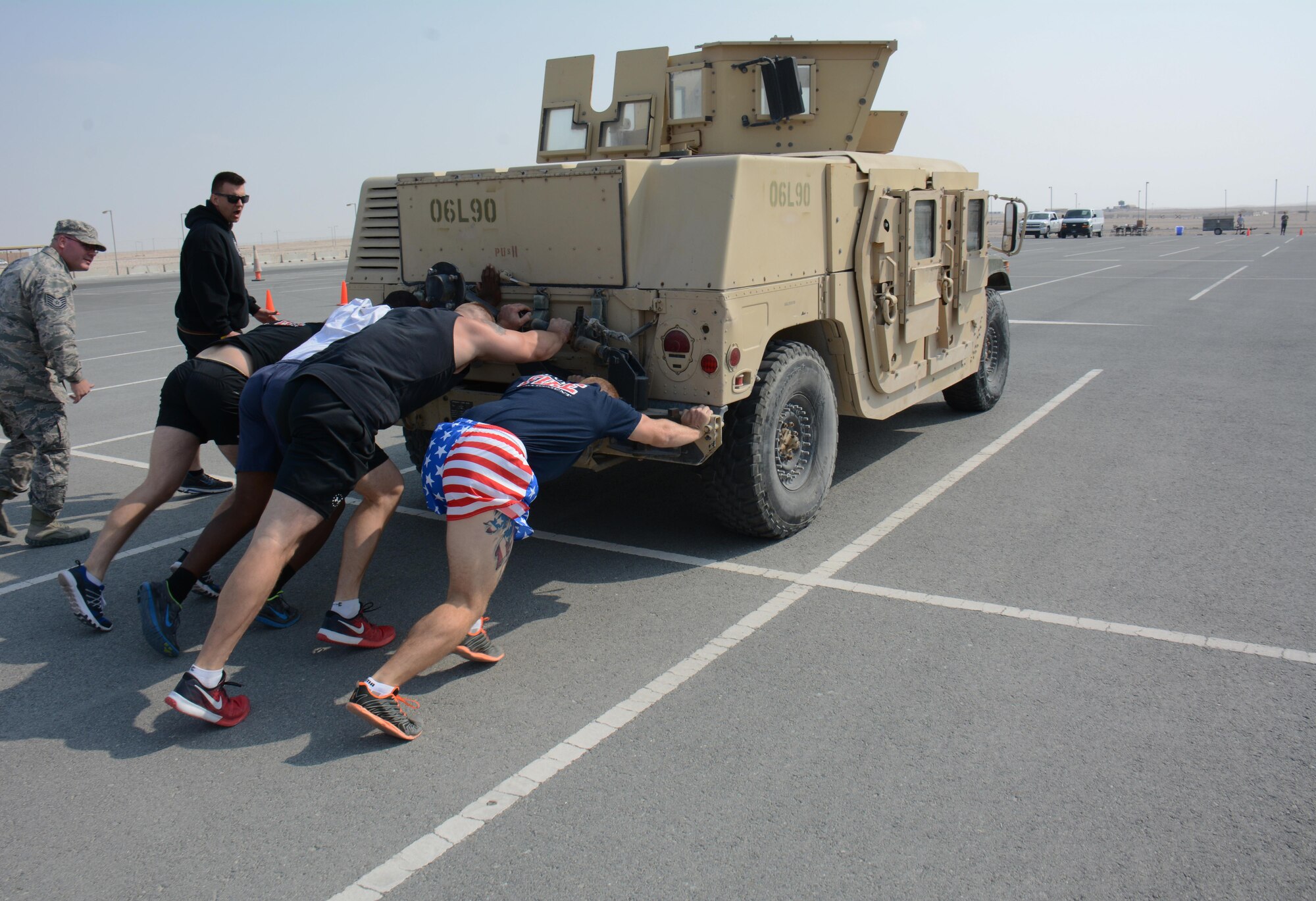 The 379th Expeditionary Civil Engineer Squadron fire team push a Humvee more than 400 feet during the fitness challenge of the annual Battle of the Badges competition at Al Udeid Air Base, Qatar Dec. 21. The team completed the fitness challenge course in 6 minutes and 16 seconds. The competition consisted of numerous events over four days including firefighter, medical and security forces career field challenges. The fitness challenge closed the event. The 379 ECES fire team took first place in the competition. (U.S. Air Force photo by Tech. Sgt. James Hodgman/Released) 
