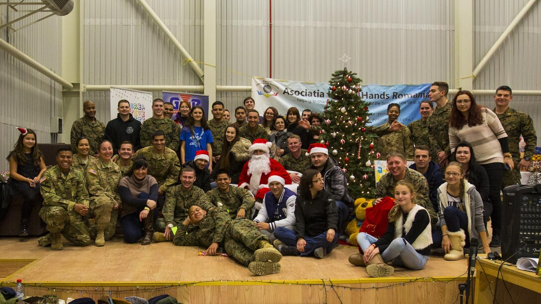 U.S. service members pose for a photo during a Christmas celebration with Romanian children on Mihail Kogalniceanu Air Base, Romania, Dec. 19, 2015. U.S. Marine Corps photo by Lance Cpl. Melanye E. Martinez