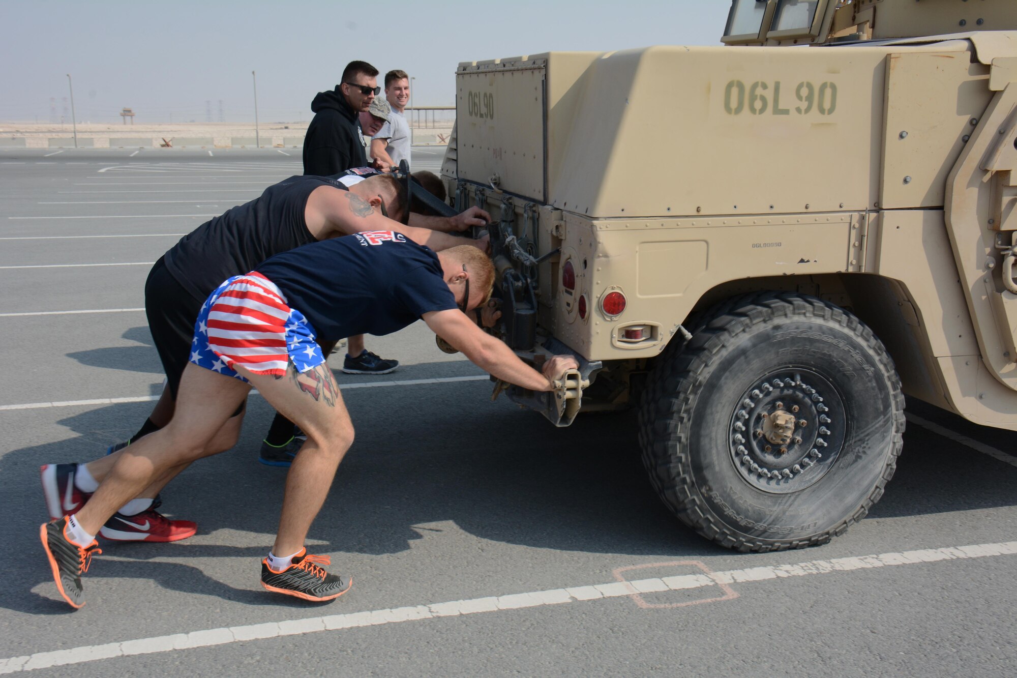The 379th Expeditionary Civil Engineer Squadron fire team push a Humvee more than 400 feet during the fitness challenge of the annual Battle of the Badges competition at Al Udeid Air Base, Qatar Dec. 21. The team completed the fitness challenge course in 6 minutes and 16 seconds. The competition consisted of numerous events over four days including firefighter, medical and security forces career field challenges. The fitness challenge closed the event. The 379 ECES fire team took first place in the competition. (U.S. Air Force photo by Tech. Sgt. James Hodgman/Released) 