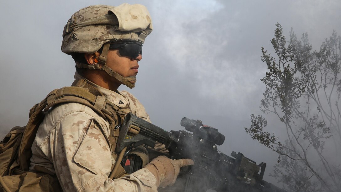 A Marine conceals himself under the obstruction of deployed smoke during the company supported, live-fire assault portion of a Marine Corps Combat Readiness Evaluation at Marine Corps Air Ground Combat Center Twentynine Palms, California, Dec. 6, 2015. The purpose of a MCCRE is to evaluate Marines’ collective performance in specific mission requirements that will prepare them for their upcoming deployment rotation. The Marine is with 2nd Battalion, 7th Marine Regiment, 1st Marine Division.