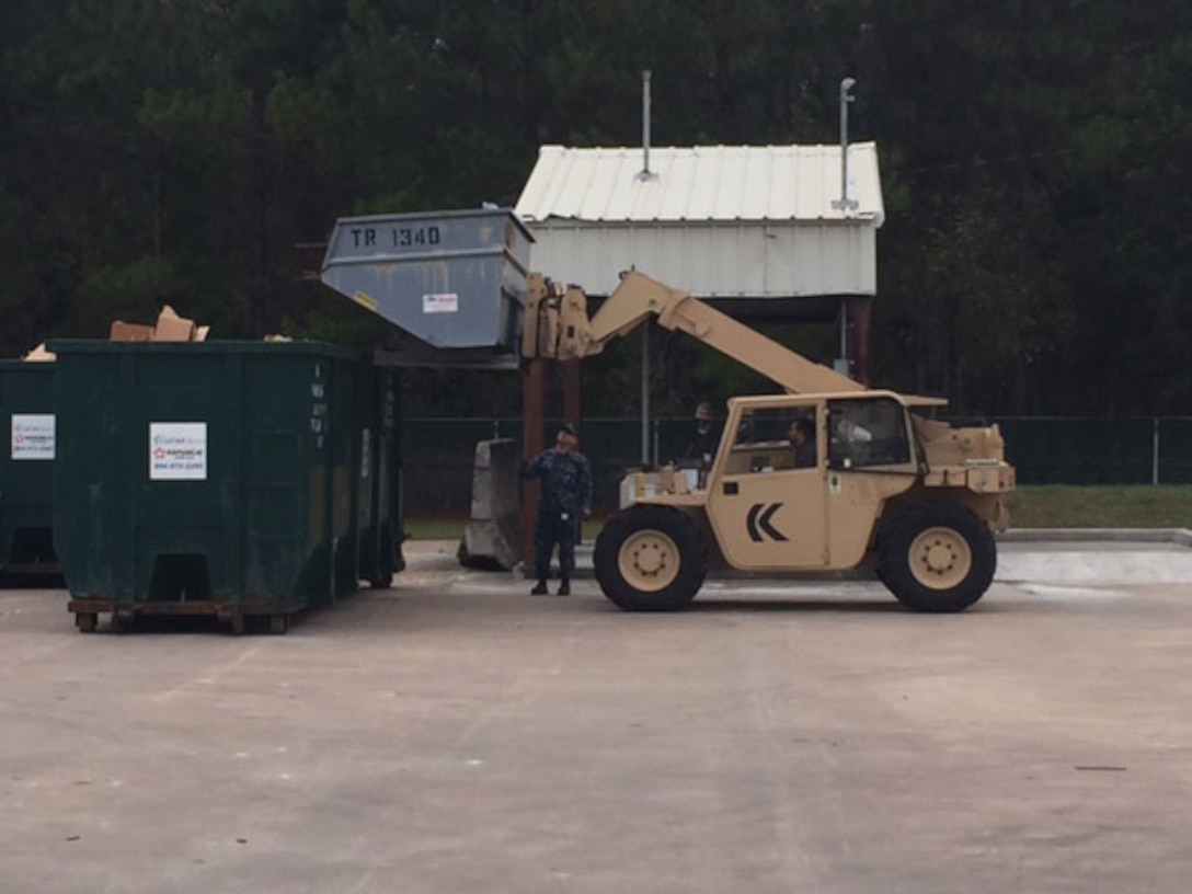 A Disposition Services Unit Six sailor (left) guides a civilian operator during training conducted for scrap loading and unloading.